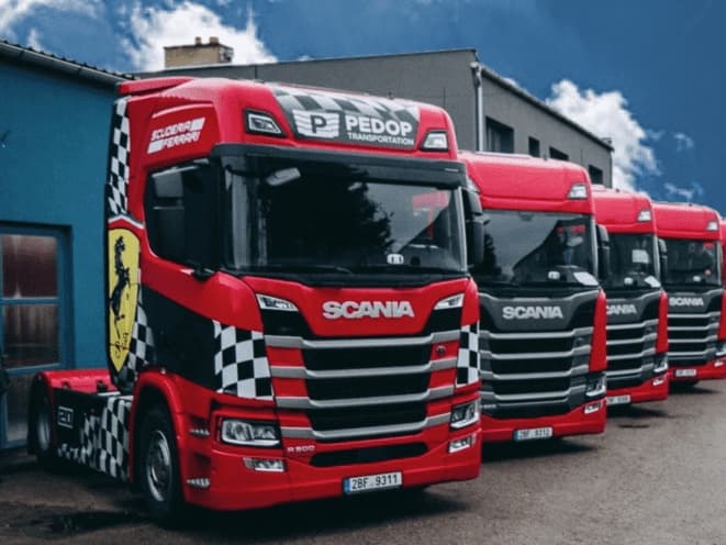 Řada tahačů Scania s nápisem PEDOP Transportation zaparkovaná v areálu firmy